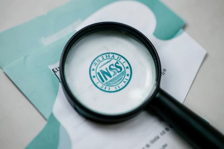 Lupa examinando um documento com selo do INSS.