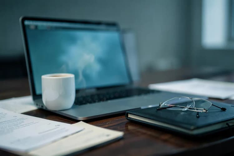 Um advogado revisando documentos em uma mesa com um laptop aberto e uma xícara de café.