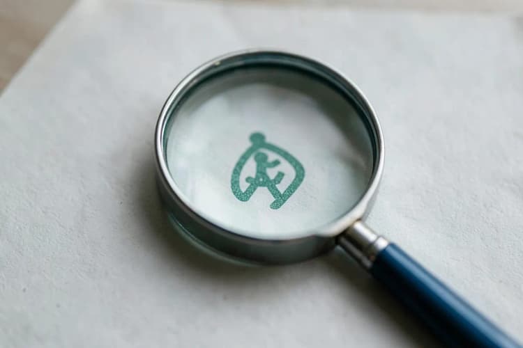 Uma lupa examinando um pequeno símbolo de acessibilidade em um papel.